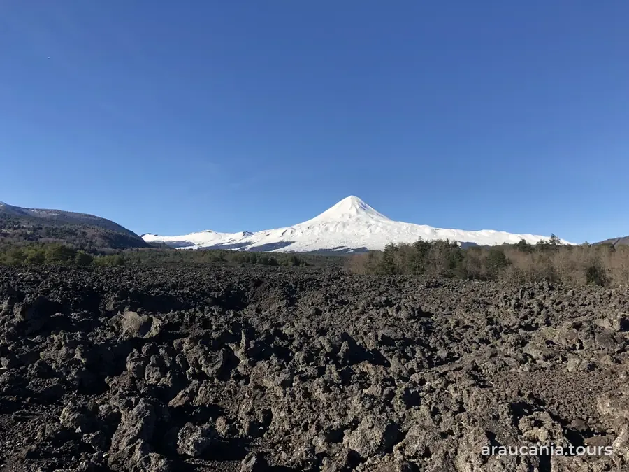 Volcán Llaima nevado detrás de un campo de lava, visto desde la comuna de Curacautín