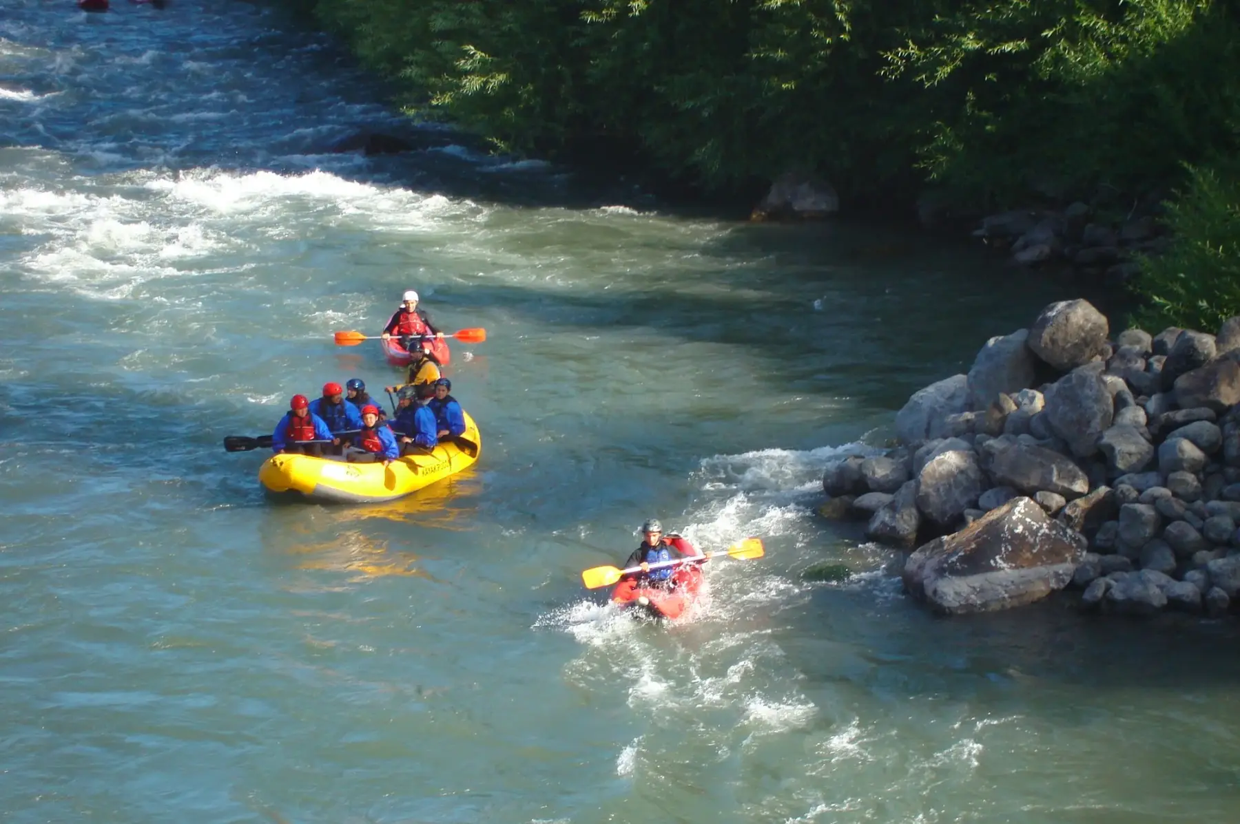 Balsa de rafting y kayaks bajando los rápidos del río Trancura, cerca de Pucón