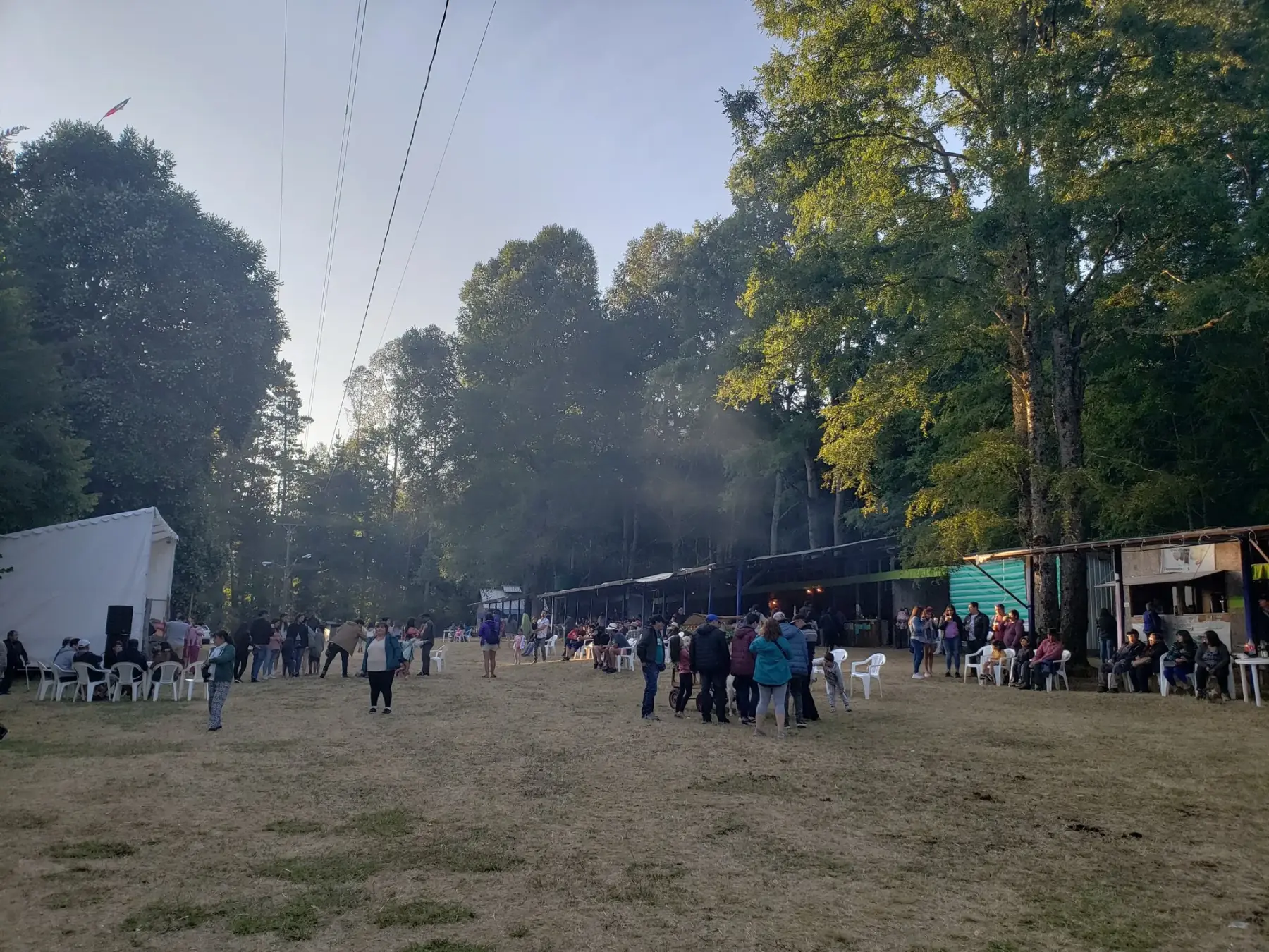 Feria costumbrista de Challupén Alto, en Villarrica, con puestos de comida y visitantes bajo los árboles